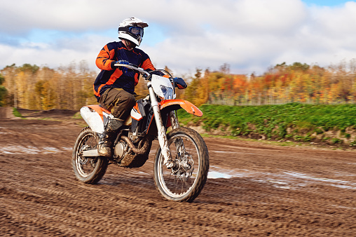 Motocross, enduro rider on dirt track. Extreme off-road race. Hard enduro motorbike. The forest behind him.