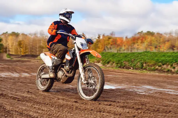 Photo of Motocross, enduro rider on dirt track. The forest behind him