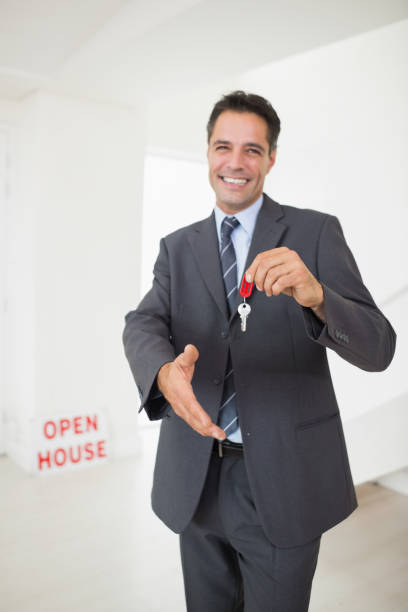 istock Businessman offering a handshake while holding up keys 690657420