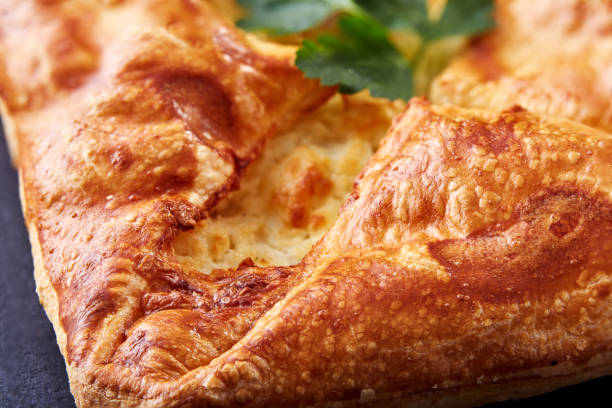istock Homemade cheese puff pastries with parsley on black background. Macro. 690675736