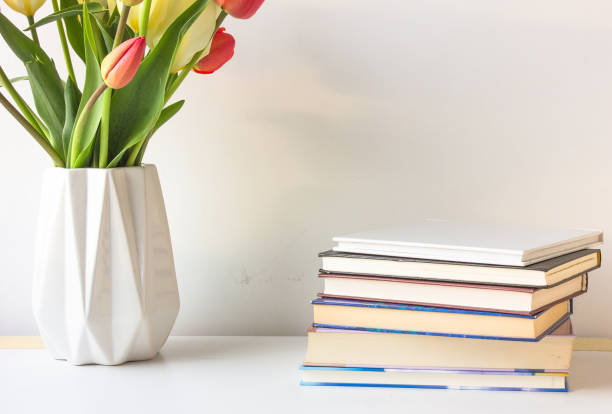 istock A stack of books and vase of spring flowers on a white background 690676298