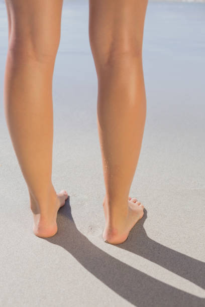 istock Womans legs standing on the sand 690687050