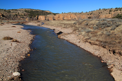 Low autumn flow of the Colorado River with steep canyon walls near Grand Junction, Colorado.