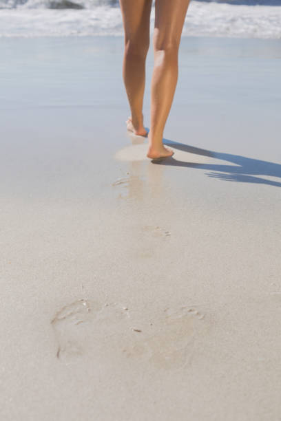 istock Womans legs standing on the sand 690687066