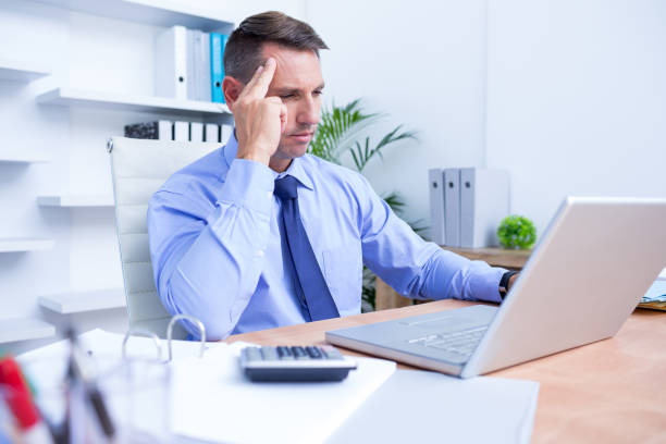 istock Businessman with severe headache sitting at office desk 690687206