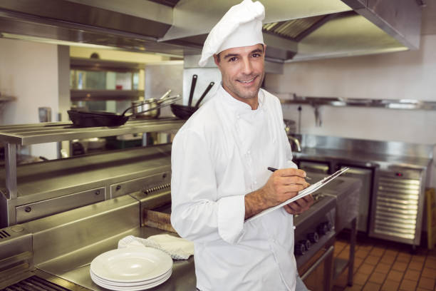 istock Smiling male cook writing on clipboard in kitchen 690690562