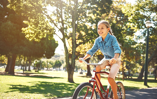 Shot of a little girl out for a ride on her bike in the park