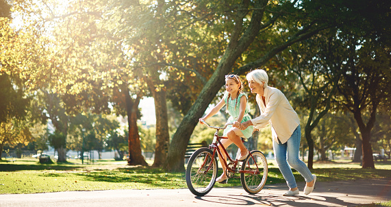 Shot of a senior woman teaching her granddaughter how to ride a bike