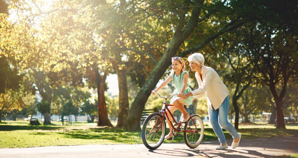 Grandma's are short on criticism & long on love Shot of a senior woman teaching her granddaughter how to ride a bike grandmother stock pictures, royalty-free photos & images