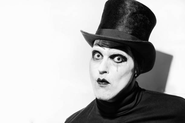 Portrait of a scary angry mime wearing a tall hat on white background.  Theatrical make-up
