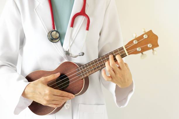 Doctor playing ukulele, Music therapy concept. stock photo