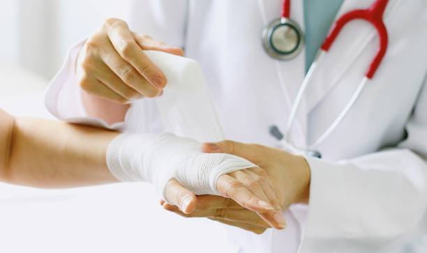 close-up of female doctor with stethoscope bandaging hand of patient. - bandage imagens e fotografias de stock