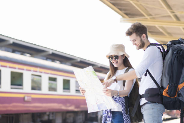 istock Couple asian and caucasian traveler backpacker are looking map for navigation direction the way, time table schedule and travel by train. Travel summer concept. 690752846