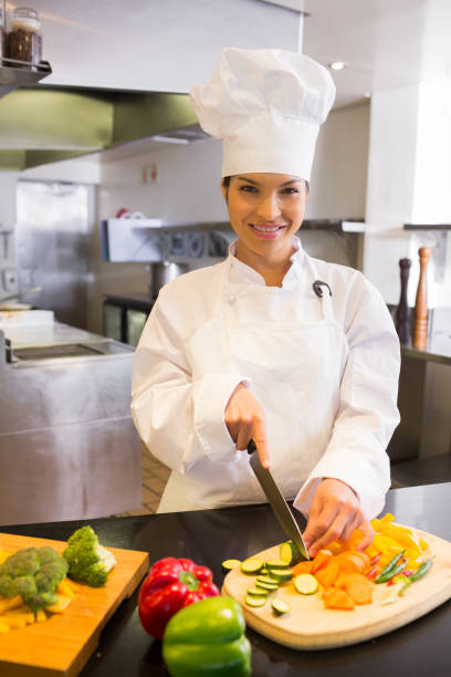 istock Smiling female chef cutting vegetables in kitchen 690760826