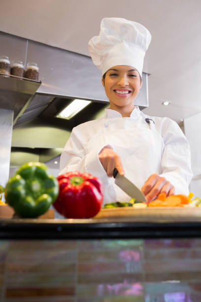 istock Smiling female chef cutting vegetables in kitchen 690760892