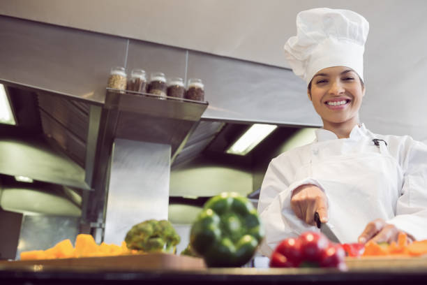 istock Smiling female chef cutting vegetables in kitchen 690760932