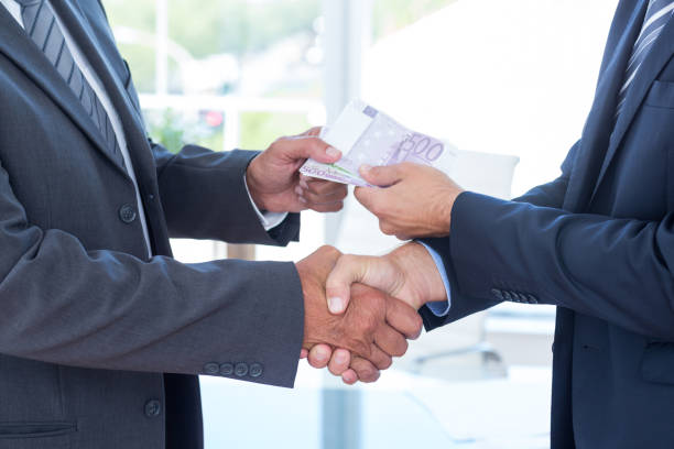 istock Businessmen shaking hands and exchanging money 690766610