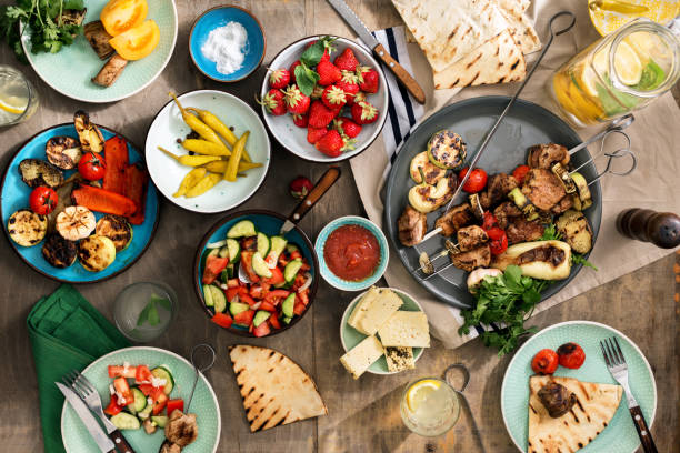 istock Dinner table concept. Shish kebab, various grilled vegetables, salad, lemonade, strawberries and snacks on a wooden table 690781322