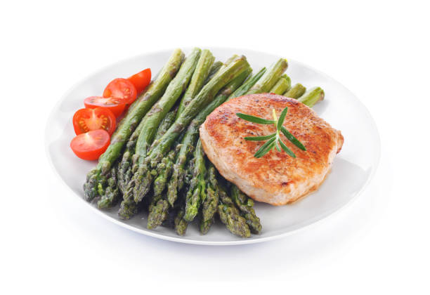 istock Cooked asparagus with meat steak and tomatoes on a white plate 690786820