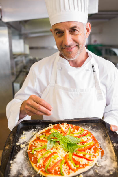 istock Confident male chef holding cooked food in kitchen 690796064