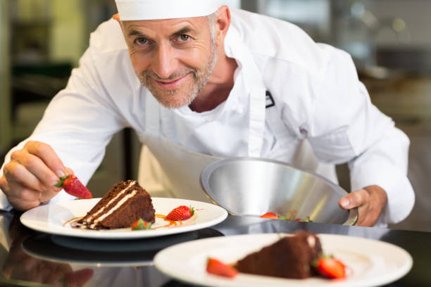 istock Smiling male pastry chef decorating dessert in kitchen 690796590