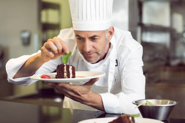 istock Concentrated male pastry chef decorating dessert in kitchen 690796804