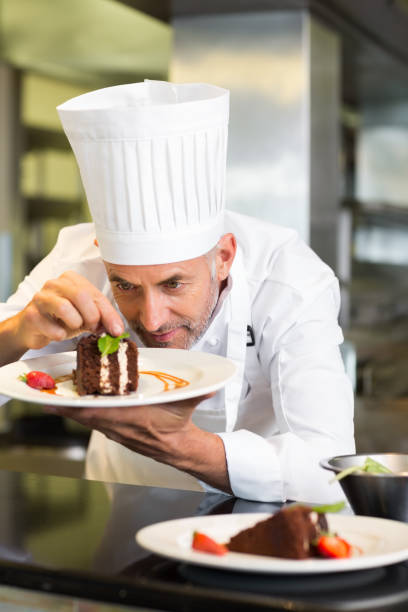 istock Concentrated male pastry chef decorating dessert in kitchen 690796980