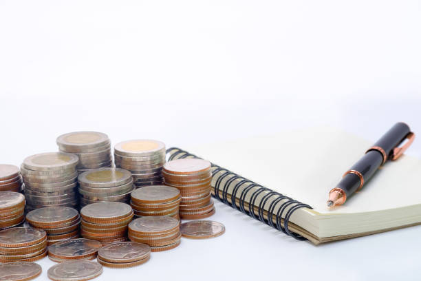 istock Close up Thai coins stack in a row with ball pen and note book on white desk for saving; finance; investment; banking concept. 690800202