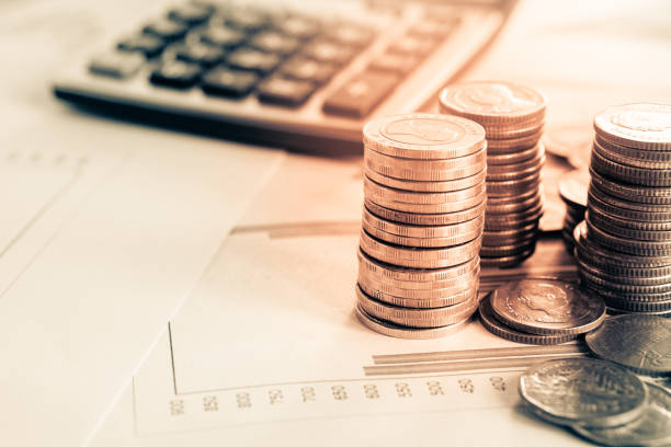 stack of coins, calculator,stock chart report and magnifying glass, business and finance concept background