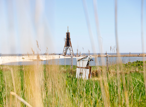 Kugelbake sea mark and beach chair seen through sea grass, Cuxhaven, Germany