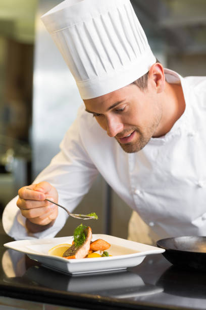 istock Smiling male chef garnishing food in kitchen 690837264