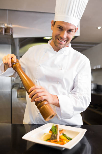 istock Smiling male cook grinding pepper on food in kitchen 690837384