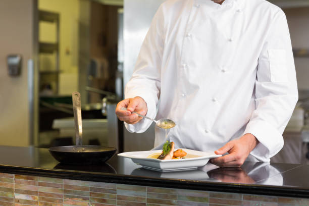 istock Mid section of a chef garnishing food in kitchen 690837448
