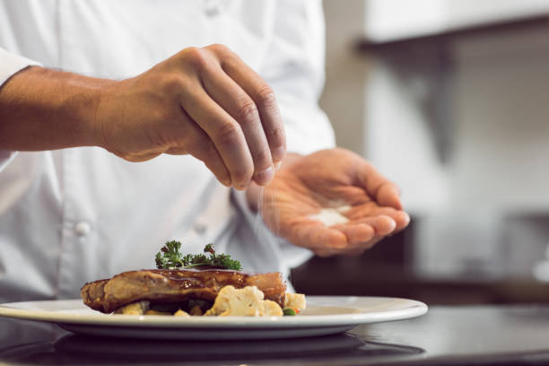 Closeup mid section of a chef putting salt Closeup mid section of a chef putting salt in the kitchen salt seasoning stock pictures, royalty-free photos & images