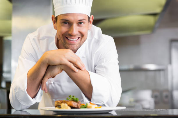 souriant chef masculin avec des aliments cuits dans la cuisine - mid adult men portrait hat human face photos et images de collection