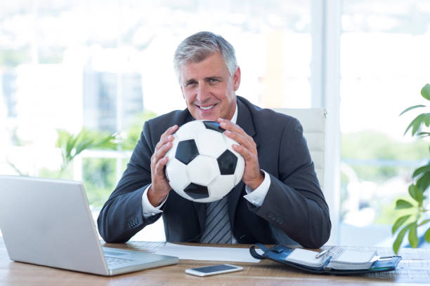 empresario sonriente sosteniendo el balón de fútbol - suit soccer men sport fotografías e imágenes de stock