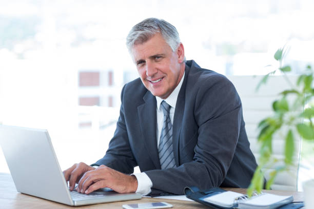 istock Smiling businessman working with his laptop 690838014