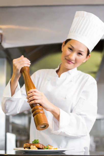 istock Smiling female cook grinding pepper on food in kitchen 690838190