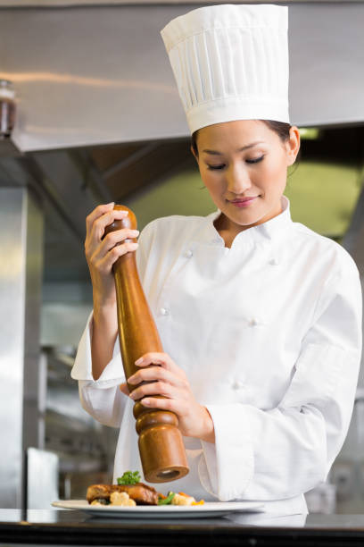 istock Female cook grinding pepper on food in kitchen 690838278
