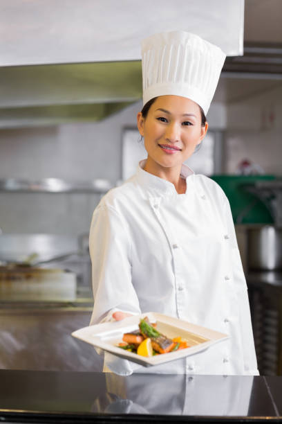istock Confident female chef holding cooked food in kitchen 690838424