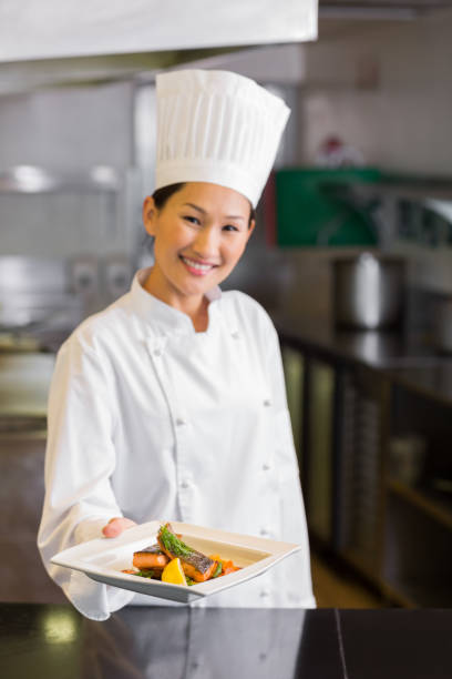 istock Confident female chef holding cooked food in kitchen 690838450