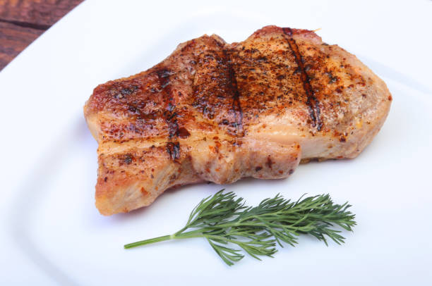 istock grilled pork chop on plate on wooden board 690840656