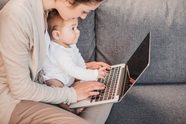 istock mother typing on laptop's keyboard with her son 690841032
