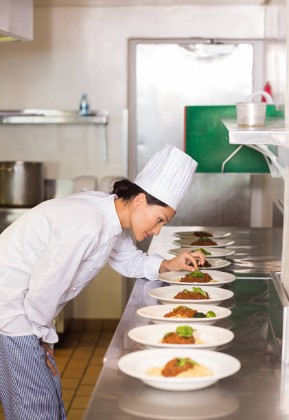 istock Concentrated female chef garnishing food in kitchen 690841064