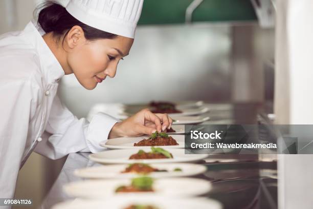 Concentrated Female Chef Garnishing Food In Kitchen Stock Photo - Download Image Now