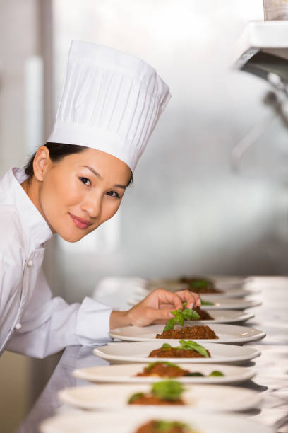 istock Smiling female chef garnishing food in kitchen 690841186