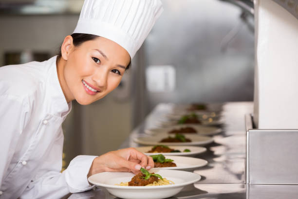 istock Smiling female chef garnishing food in kitchen 690841400