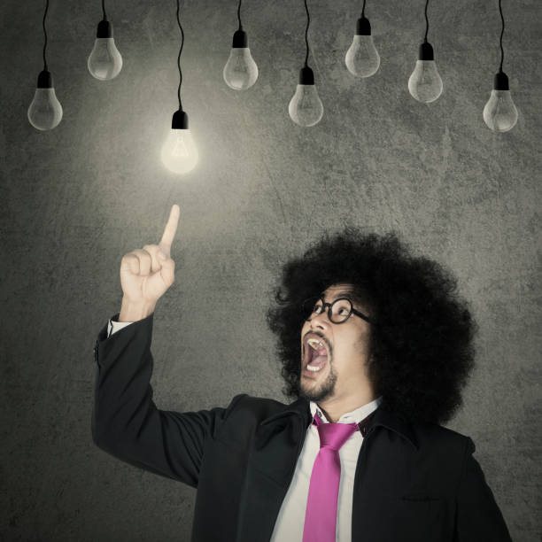 istock Afro businessman chooses light bulb 690853008