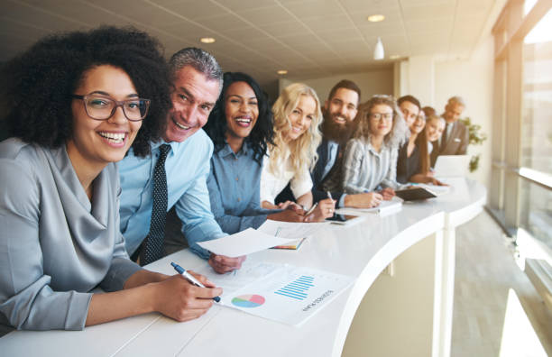 Cheerful multiracial colleagues looking at camera in office Smiling black and white coworkers looking at camera in the office. business people stock pictures, royalty-free photos & images