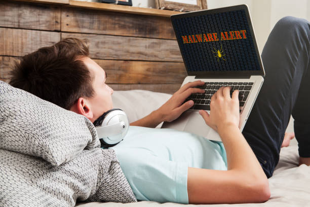 istock Malware alert in a laptop computer being used by man at home. 690856010